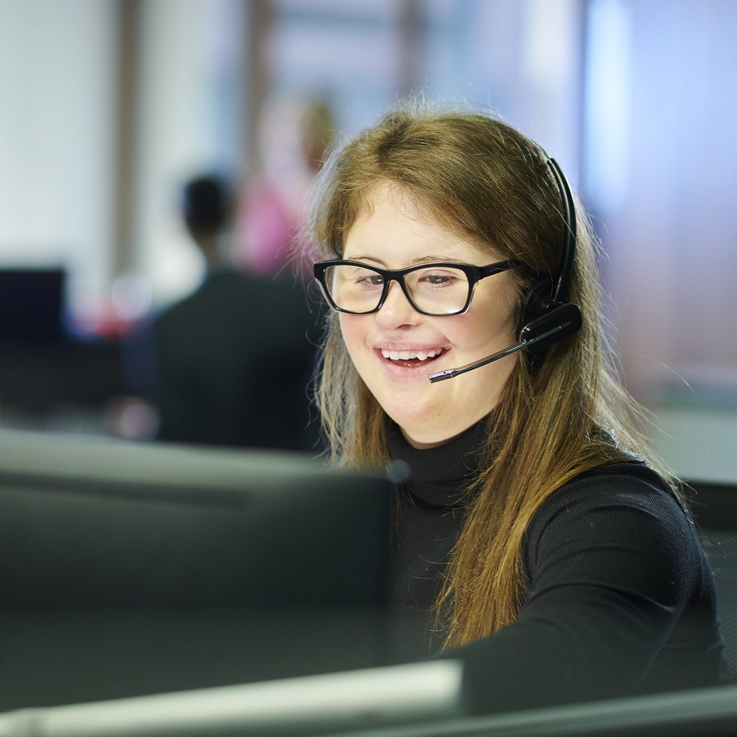 A woman with a disability with a headset on in an office